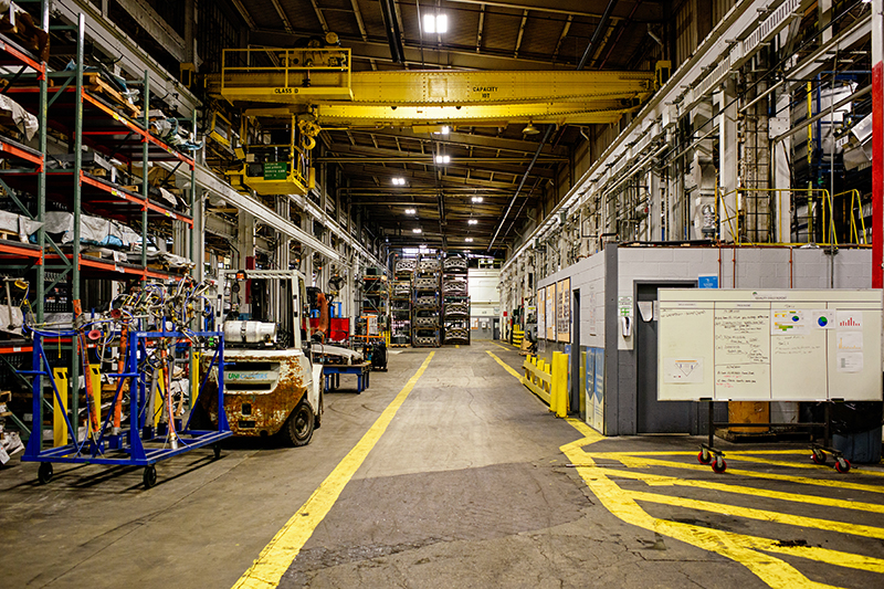 A wide shot of the New Center Stamping facility showing a white board to the right and shelves of materials and equipment to the left